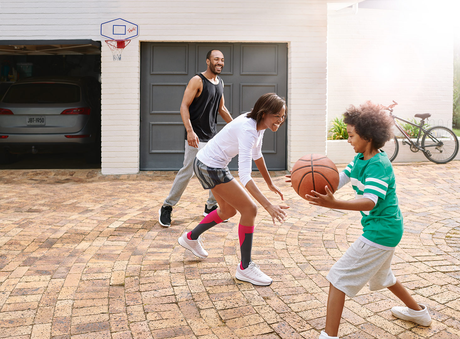 Boy holding a basketball and playing with his mum and dad on his driveway