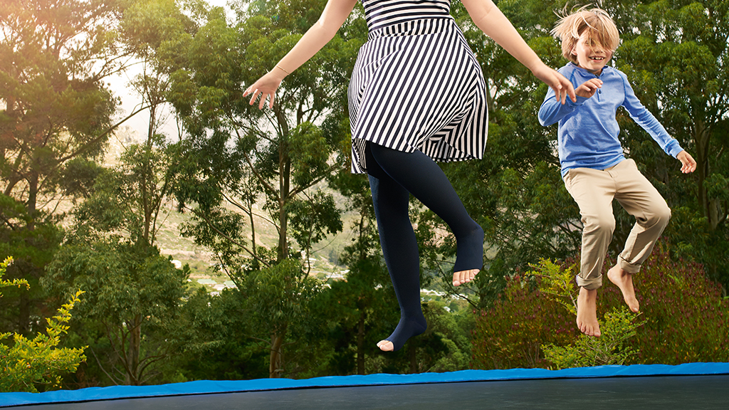 Mum and son bouncing on trampoline in the garden